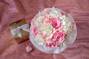 Noble bouquet of white and pink roses with gift basket made of golden paper isolated on pink background.