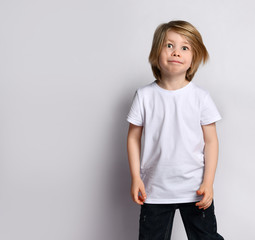 Little blond bro in black and white casual wear. He is smiling, posing on a white background. Childhood, fashion, advertising.