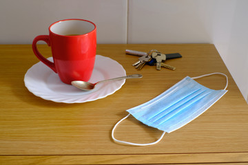 Mask, keys and coffee on wooden table