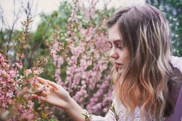 Fototapeta premium Girl in a delicate dress with mehendi on the body, in flowering almonds