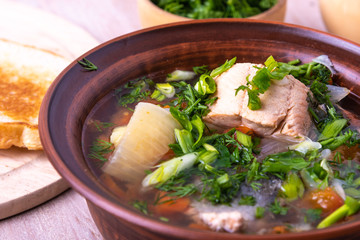 Simple fish soup with salmon and vegetables in a clay bowl