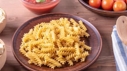 Classical Italian fusilli on a plate and ingredients for making pasta with cheese and tomatoes