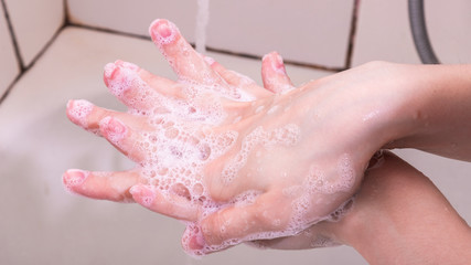Fototapeta premium Woman washes hands with liquid soap, soap suds, close-up