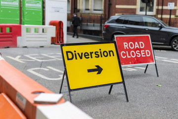 Yellow Road Sign with Arrow: Diversion Text and Barrier
