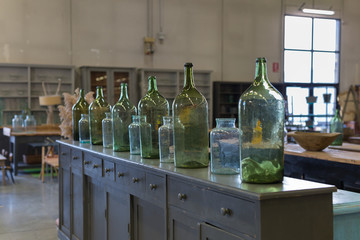 Six Green, Empty and Dirty Glass Bottles over an Antique Wooden Chest of Drawers