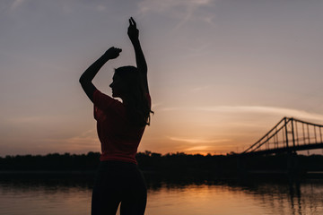 Portrait from back of graceful girl standing on nature background in evening. Outdoor shot of...