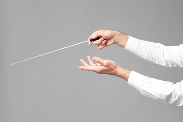 Hands of senior male conductor on grey background