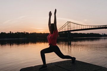Full-length portrait of happy slim girl doing yoga on nature background. Outdoor shot of pleased...