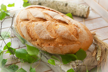 Traditional whole wheat bread on rustic wooden table with birch branche