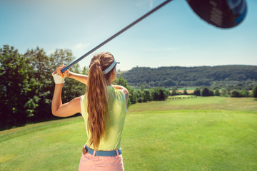 Woman with driver on golf course at the tee