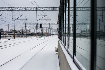 Zimowy dworzec kolejowy odbijający się w szybie.