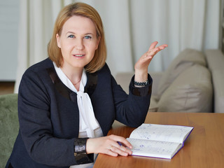 a businesswoman in a white blouse and dark jacket asks a question. the diary is in her hands