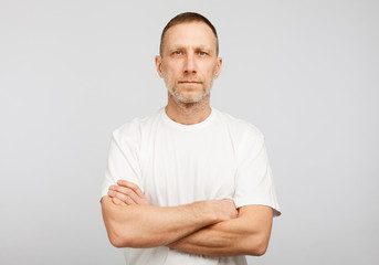 Man in white t-shirt with arms crossed on white background