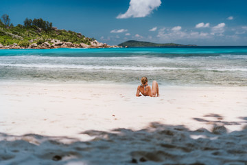 Fototapeta na wymiar Young tanned woman enjoying tropical sandy beach Anse Cocos at La Digue Island, Seychelles