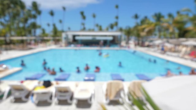 Out of focus people having fun at outdoor poolside at tropical resort. Blurred. Defocused travel background