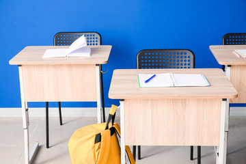 Modern school desks near color wall