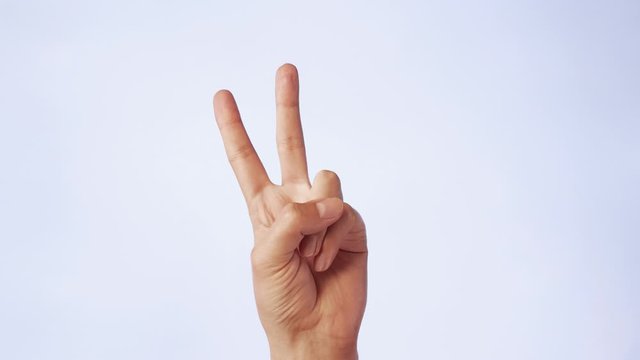 Two fingers on a hand raised up as symbol of victory. Popular and famous hand gesture on white isolated background. Closeup gesture two fingers in badge of world