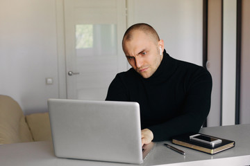 Fototapeta na wymiar Pensive short haired man sitting at tablework at laptop thinking of problem solution, thoughtful male employee pondering considering idea looking at computer screen making decision