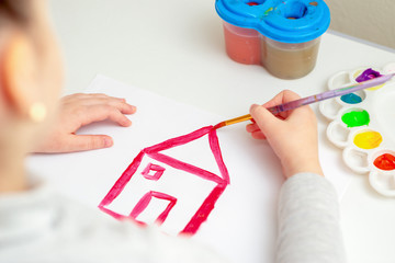 The hand of child drawing a house roof on white paper. Concept of creative learning.
