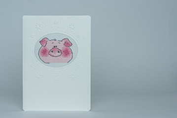 Embroidered handmade postcard by cross-stitch pattern. Muzzle pig.