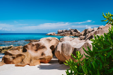 La Digue, Seychelles. Beautiful remote tropical beach with green foliage, unique granite rocks and...