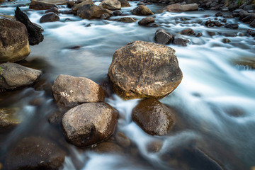 A long exposure photo of a river and a brown rock in the central Drakensberg South Africa