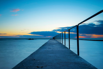 Cloudy spring sunset over ocean and jetty, Sweden