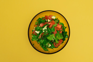 A salad of lettuce, tomatoes and other vegetables on the yellow background