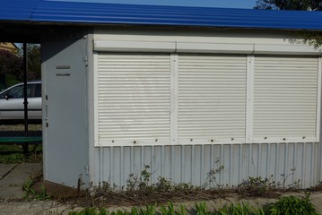 gray metal building with windows closed by white roller blinds 