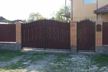 iron  gate with  forged pattern and brown metal fence in the street