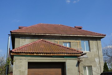 private gray house with windows under a brown tiled roof against a blue sky