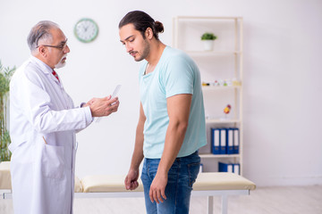 Obraz premium Young back injured man visiting experienced male doctor