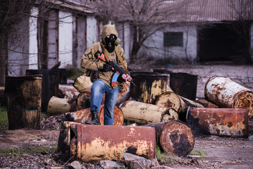 Armed stalker warrior in gas mask in destroyed chemical factory