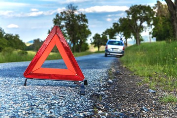 Red emergency stop sign and broken silver car on the road. Warning triangle on a country road in the Czech Republic.