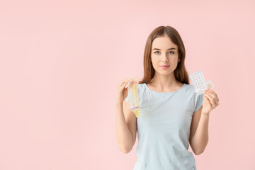 Young woman with different means of contraception on color background