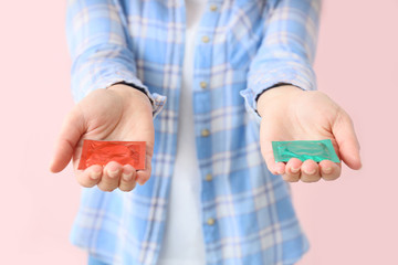 Young woman with condoms on color background, closeup