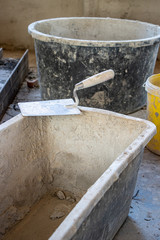  trowel lies on the edge of a mortar box on a building site