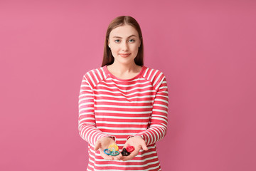 Young woman with condoms on color background