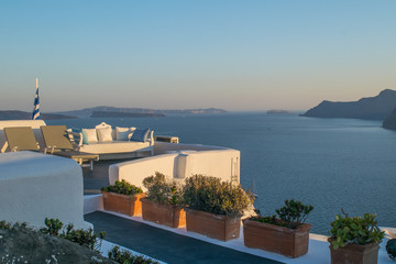 Terracotta planters with shrubs on a white wall in Oia with Santorini's caldera in the background