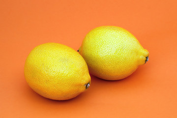 two lemons orange background yellow citrus fresh fruits