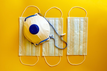 Respirator and surgical face masks on yellow background