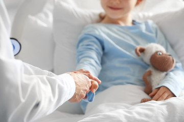 Fototapeta premium Female doctor working with little girl in hospital room, closeup