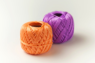 Two skeins of thread in purple and orange. Knitting threads on a white background. hobby.