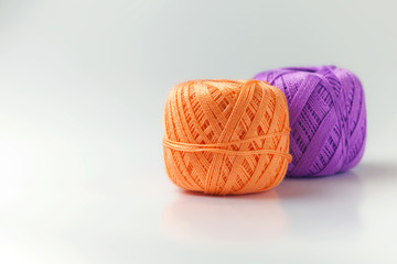 Two skeins of thread in purple and orange. Knitting threads on a white background. hobby.
