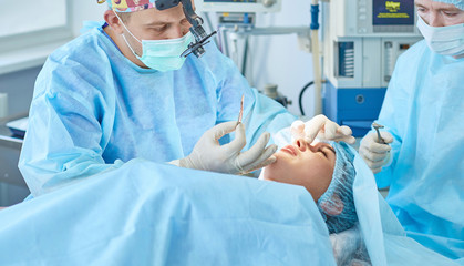 Several doctors surrounding patient on operation table during their work. Team surgeons at work in operating room