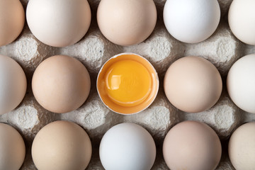 Chicken eggs in organic packaging closeup. Egg half broken among other eggs. Food photography