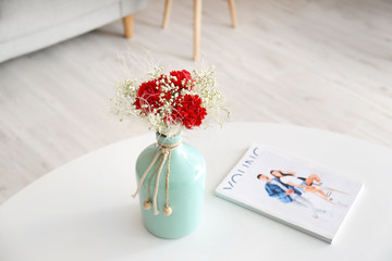 Vase with bouquet of beautiful flowers on table in room