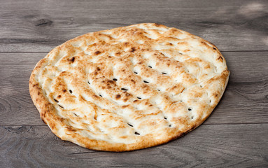 Oven baked fresh pita bread on wooden table. Trendy middle eastern flatbread on rustic wood surface. 45 degrees angle.