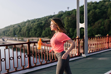 Winsome european girl with bottle of water running around city. Outdoor photo of positive young...