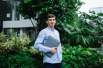 Confident student near green shrubs